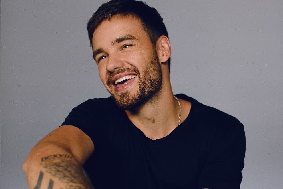Studio photograph of Liam Payne smiling and looking off camera.