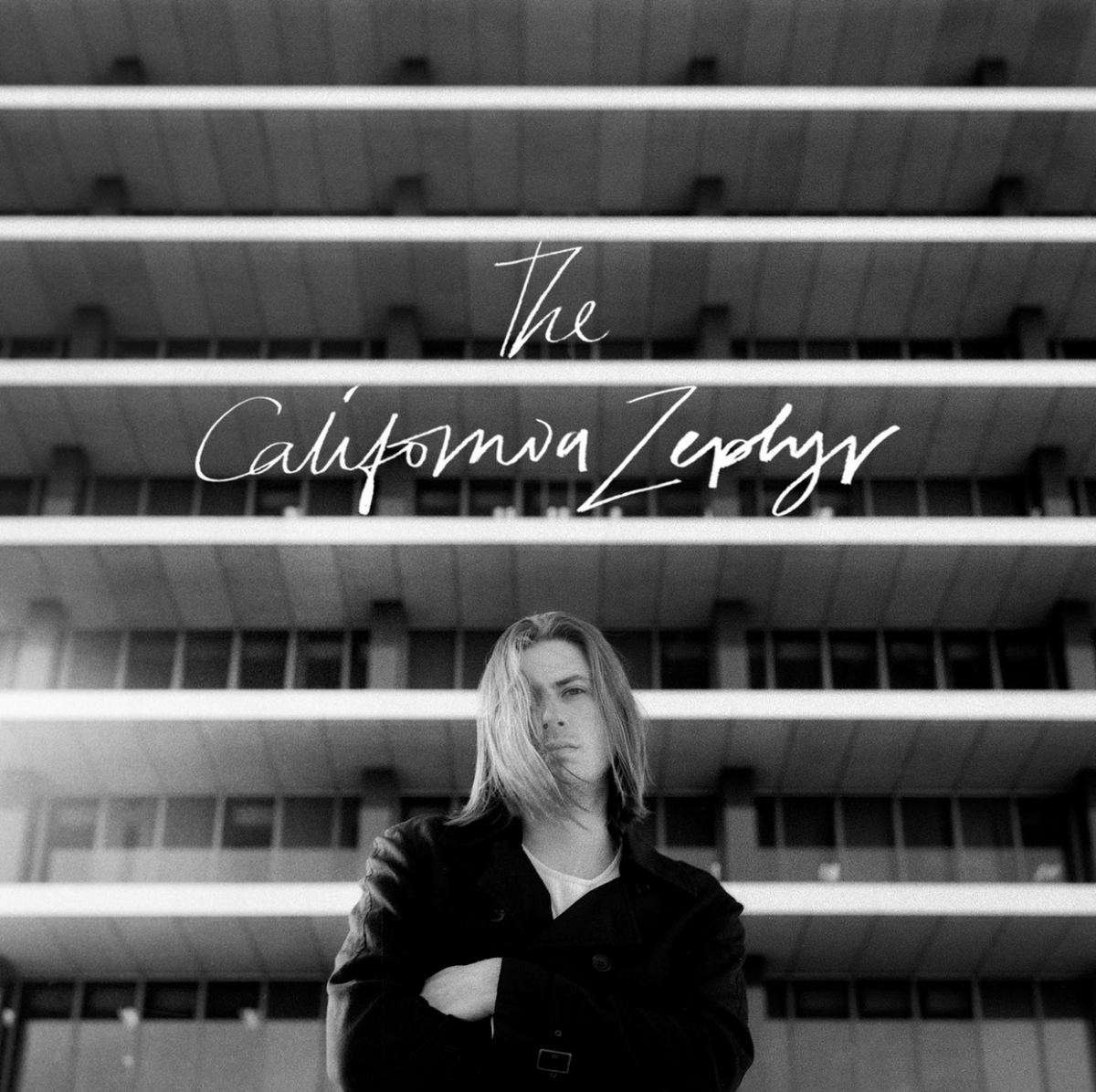 The California Zephyr cover art. Black and white image of Merrick Winter standing with arms crossed in front of a building.