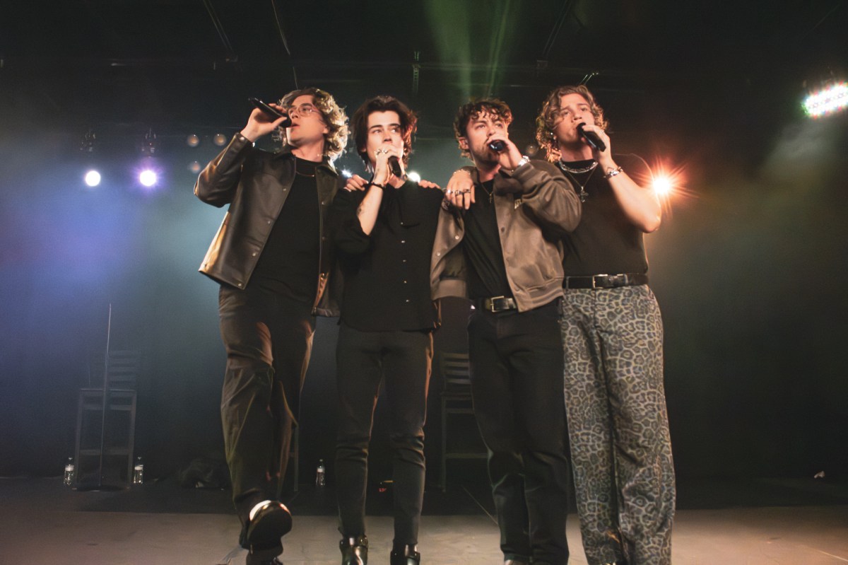 The four members of Midnight Til Morning stand shoulder to shoulder on stage.